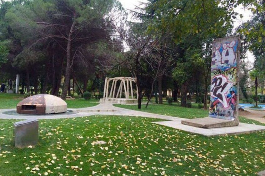 A park with a playground, a graffiti-covered pillar, and a dome-shaped structure. 4