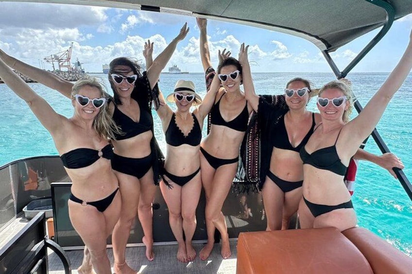 Een groep mensen in een boot, met de oceaan en een schip op de achtergrond. 2