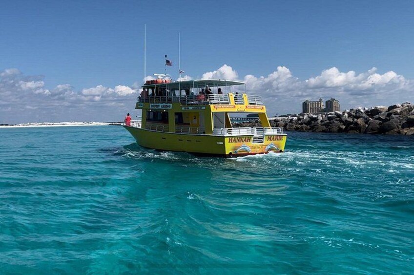 Un bateau jaune, baptisé « Hannah Marie », navigue sur une eau turquoise, avec une côte rocheuse et un ciel dégagé en arrière-plan. 2