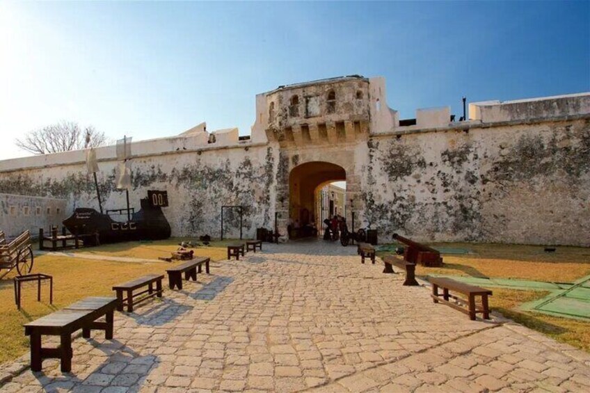 A historical fort with cannons and a paved courtyard with benches. 2