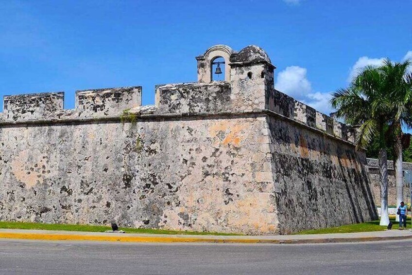 A historic stone fort with a bell tower and a palm tree in the background. 5