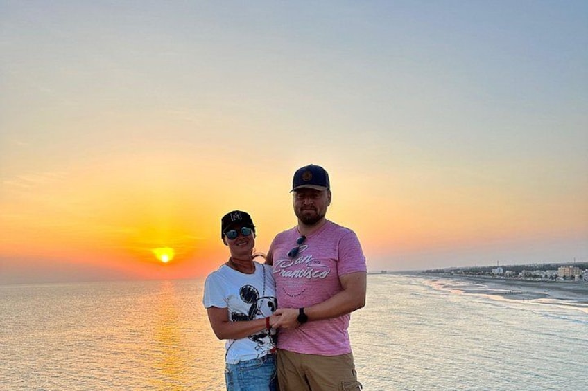 Zwei Personen stehen am Strand, im Hintergrund ein Sonnenuntergang. 4