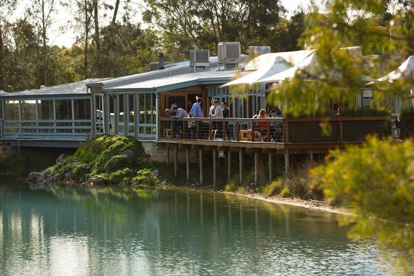 A lakeside restaurant with outdoor seating, a dock, and a bridge. 2