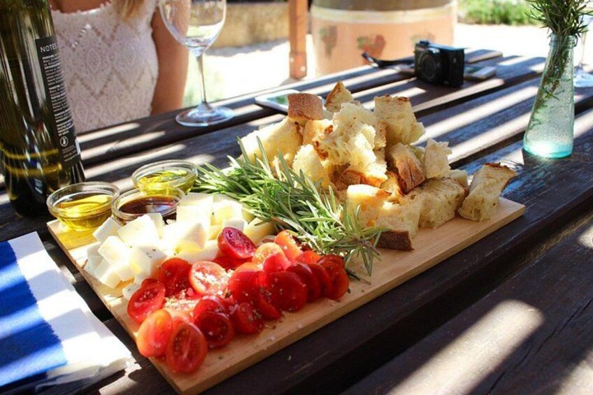 A wooden board with cheese, tomatoes, and bread on a picnic table. 3