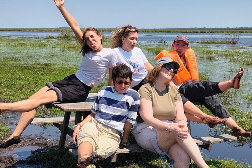 A group of people sitting on a wooden bench by a water body. 2