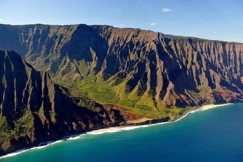 A coastal mountain range with steep cliffs and a turquoise ocean. 3