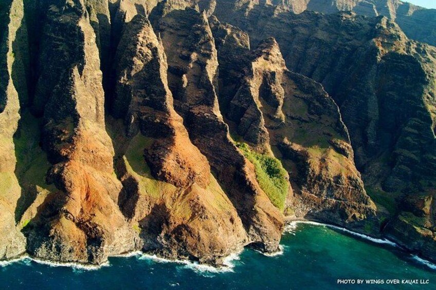 A coastal cliff with steep, rugged terrain and a clear view of the ocean. 2