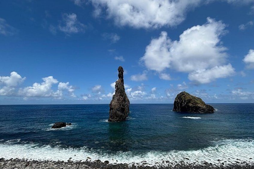 A coastal landscape with a prominent rock formation in the water and a smaller rock on the shore. 3