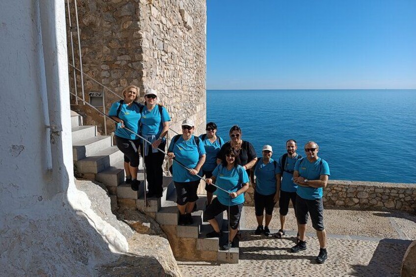 A group of people in blue shirts walking up stone steps by the sea. 3