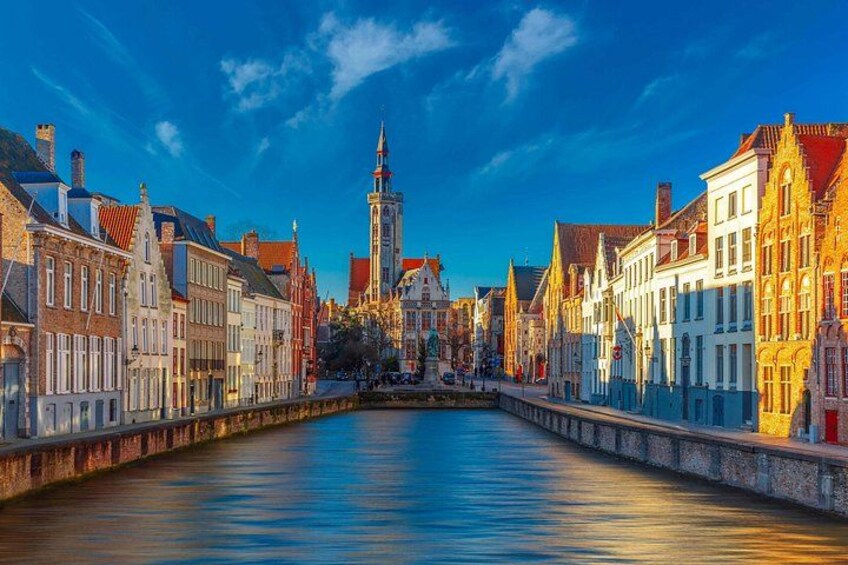 Un canal flanqueado por edificios, un puente y una torre a lo lejos. 5