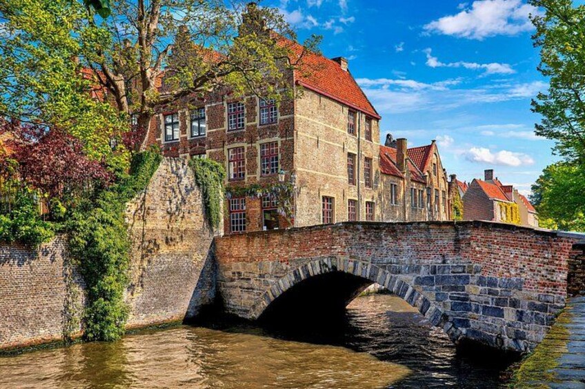 Un puente de piedra sobre un río, edificios históricos con tejados rojos y abundante vegetación. 4