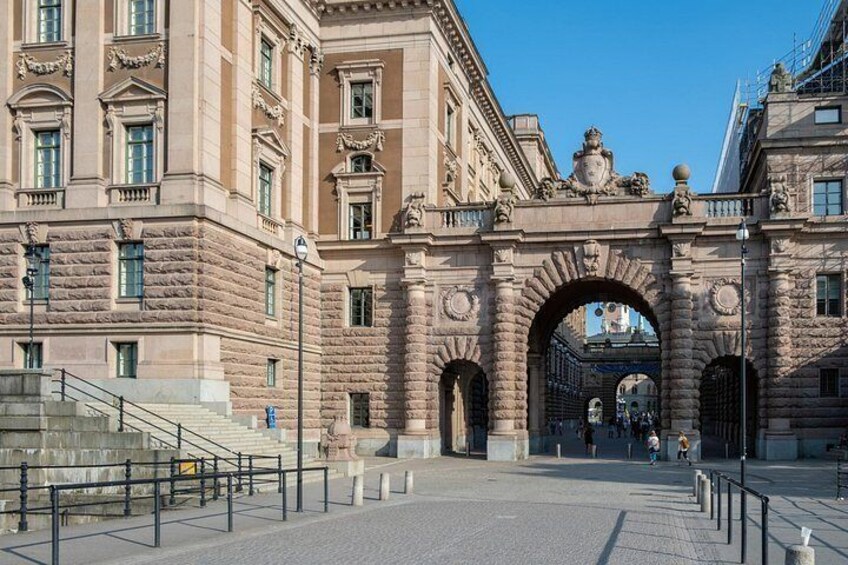 Un arco de piedra histórico con intrincadas esculturas y una escalera que conduce a un edificio. 3