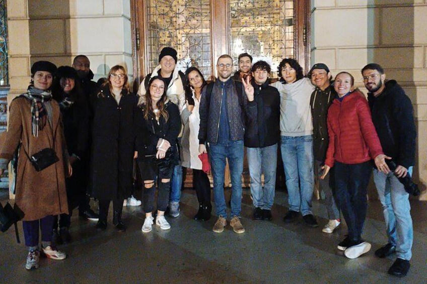 Un grupo de personas de pie frente a un edificio con amplias ventanas y una entrada decorativa. 5
