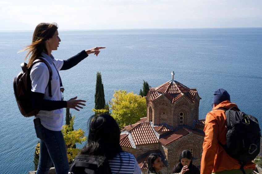 A group of people on a hill overlooking a coastal town with a prominent church. 2