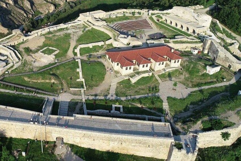 An aerial view of a historical fort with a central building, surrounding walls, and a bridge. 2