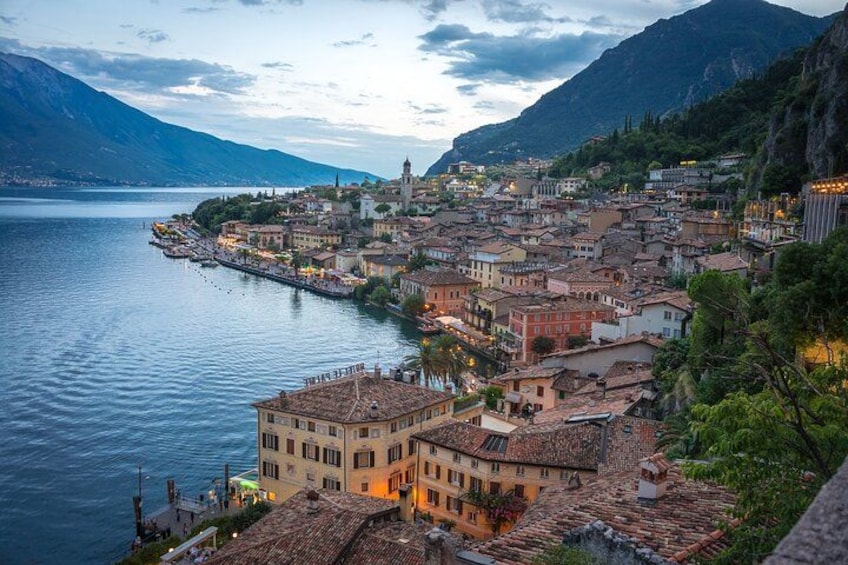 A lakeside town with historic buildings, a prominent church, and mountains in the background. 1