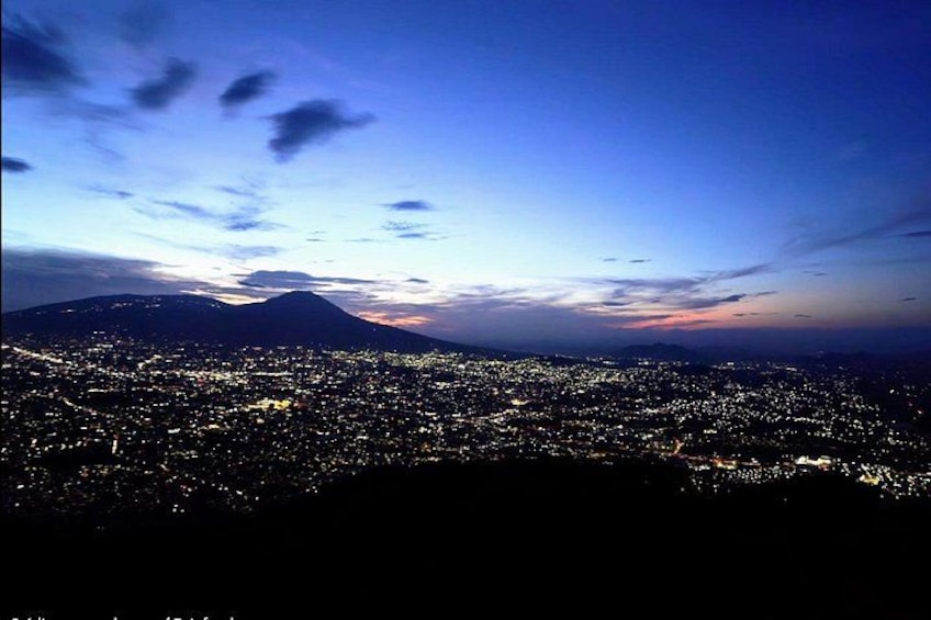 A city at dusk with a mountain in the background. 1