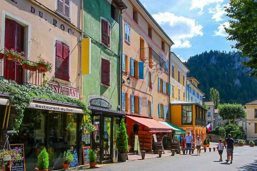 A street with colorful buildings, a restaurant, and people walking. 3