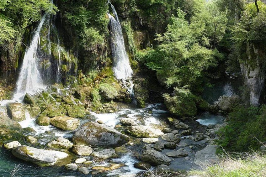 A waterfall, rocks, and a forested area. 2