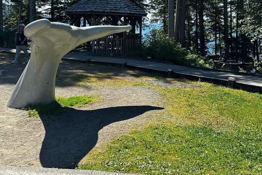 A large whale bone sculpture in a park with a wooden structure in the background. 2