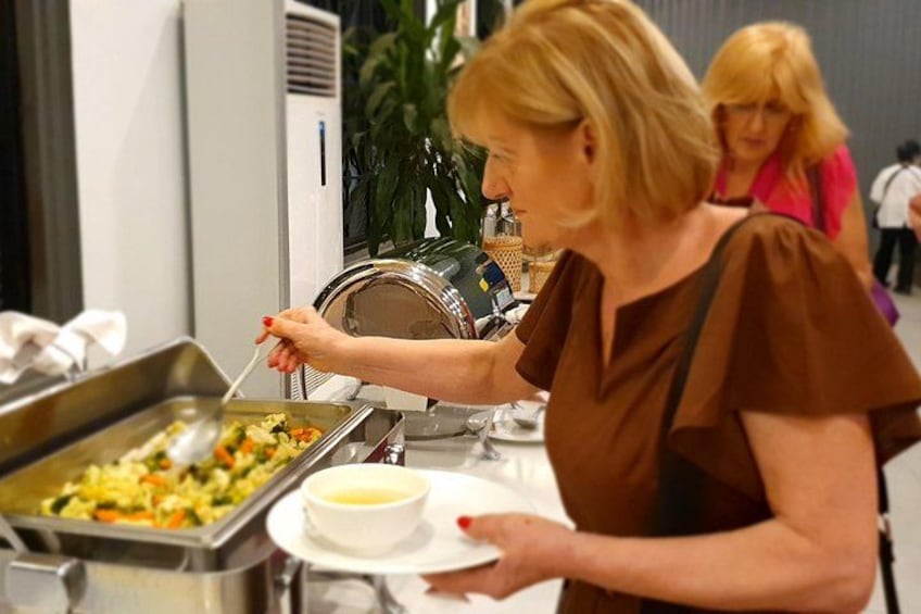 A buffet table with food containers and a bowl of soup. 2