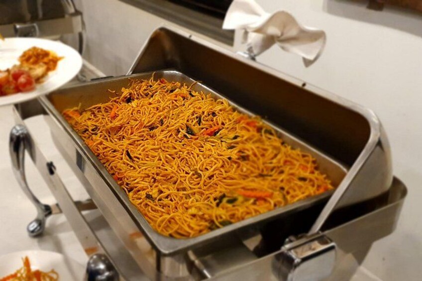 A buffet table with a large tray of noodles. 3