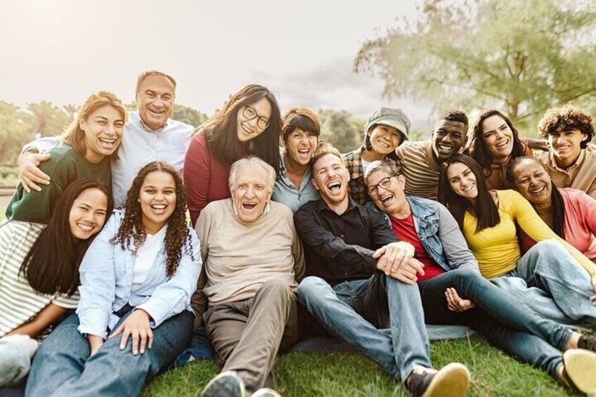 A group of people sitting on grass outdoors, some on a blanket. 3