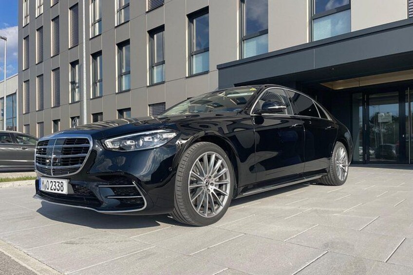 Un sedán negro estacionado frente a un edificio moderno con grandes ventanales. 2