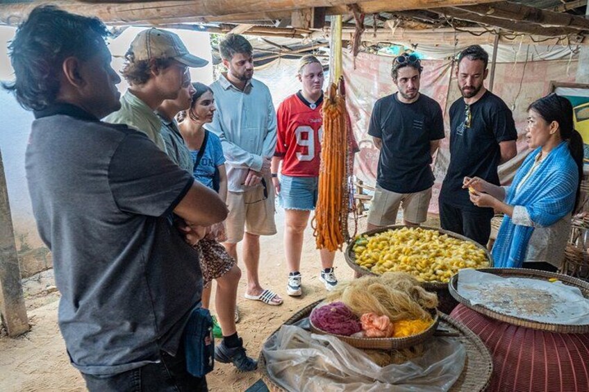 A group of people standing around a food stall with various fruits and vegetables on display. 3