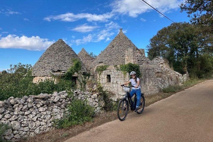 Un cycliste sur une route asphaltée, avec des bâtiments en pierre en arrière-plan. 1
