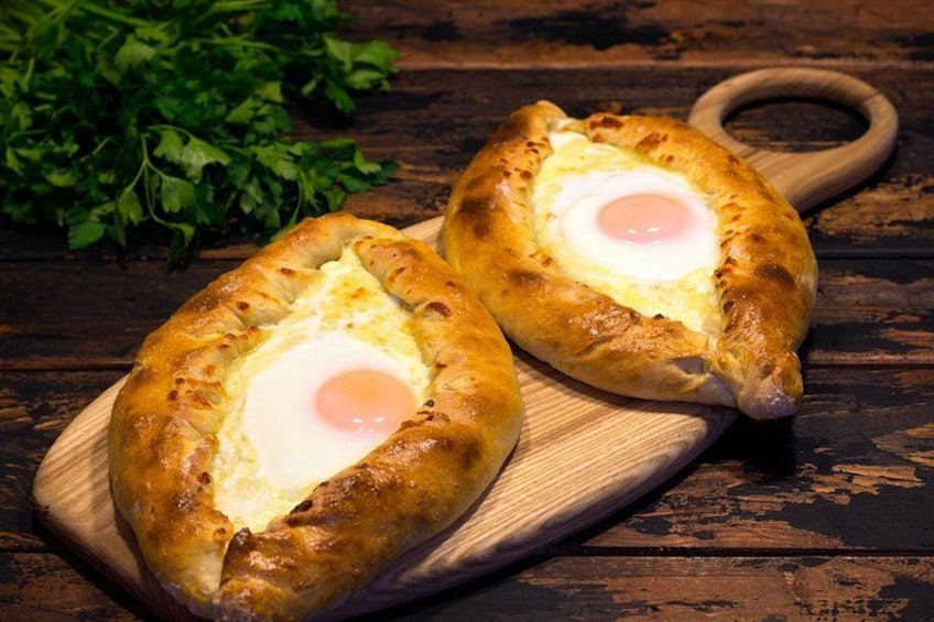 Two oval-shaped bread with a fried egg in the center, placed on a wooden board. 4