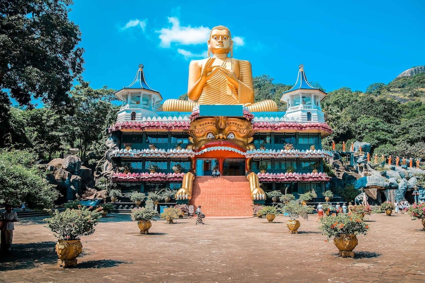 A large golden Buddha statue in front of a traditional building with a red staircase leading up to it. 5