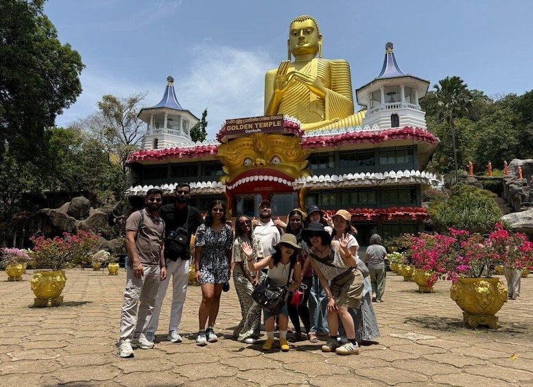 Un groupe de personnes se tient devant un temple, où se trouve une grande statue dorée et une pancarte sur laquelle on peut lire : « TEMPLE D’OR ». 1