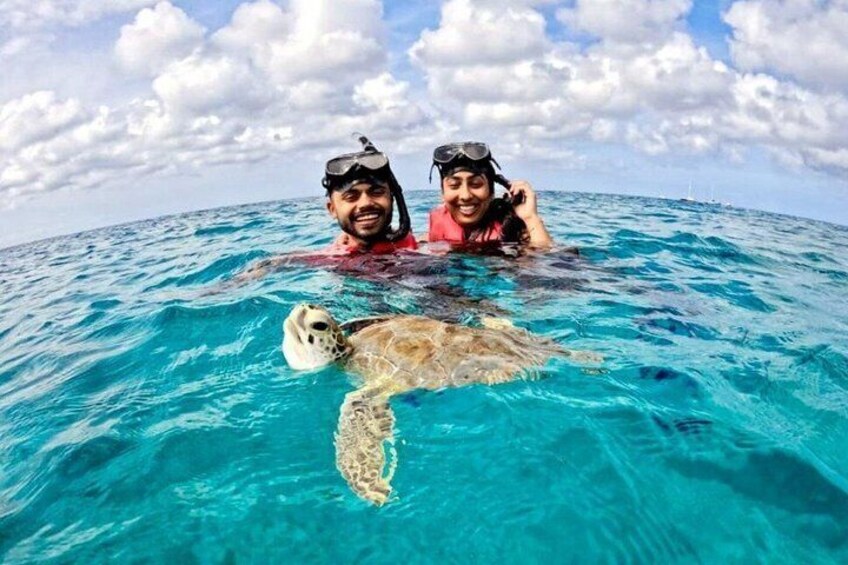 Two people snorkeling with a sea turtle in clear blue water. 1