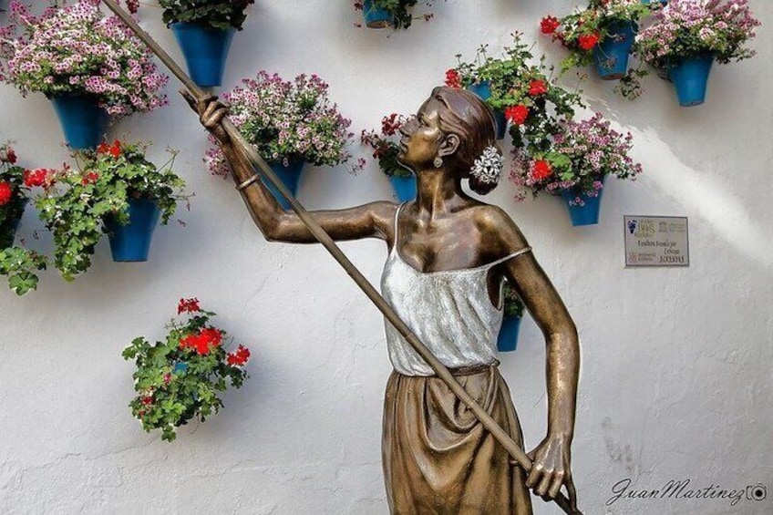 Una estatua de bronce de una mujer sosteniendo un tridente, rodeada de plantas en macetas. 5