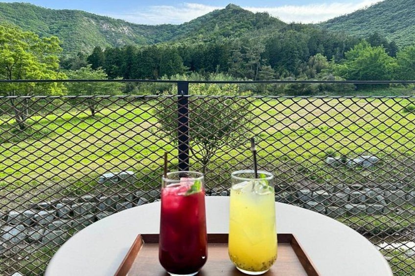 A table with two drinks and a scenic mountain view in the background. 5