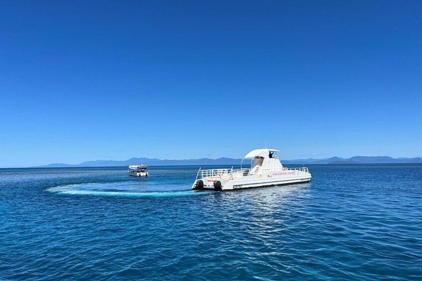 A white boat on calm blue waters with a clear sky and distant mountains. 3