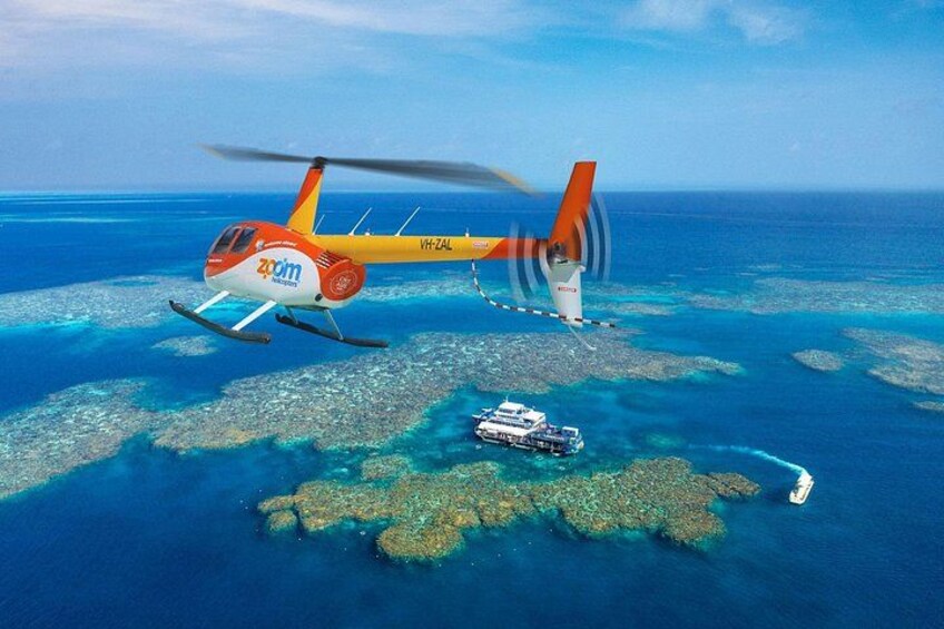 A helicopter flying over a coral reef with a boat below. 3