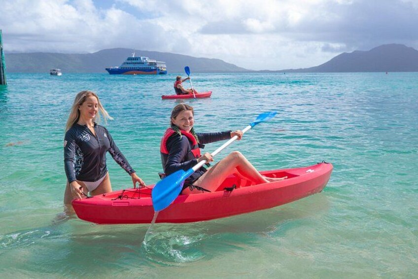 Two people in a red kayak on a calm sea with a boat in the background. 4