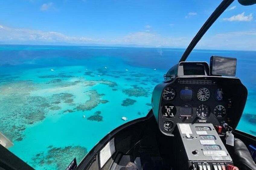A helicopter cockpit with a view of turquoise waters and coral reefs. 2