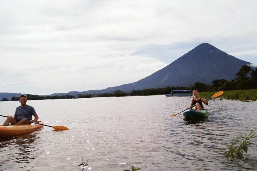 Two people kayaking on a calm river with a mountain in the background. 3