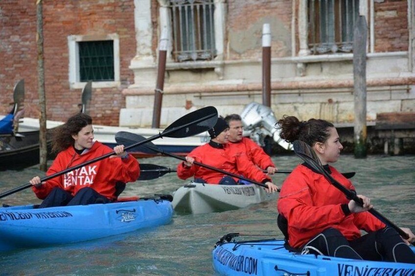 Persone con giacche rosse che paganoano kayak su un canale. 1