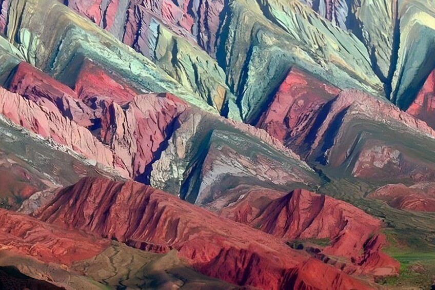 A colorful mountain range with distinct layers of red, green, and brown hues. 1