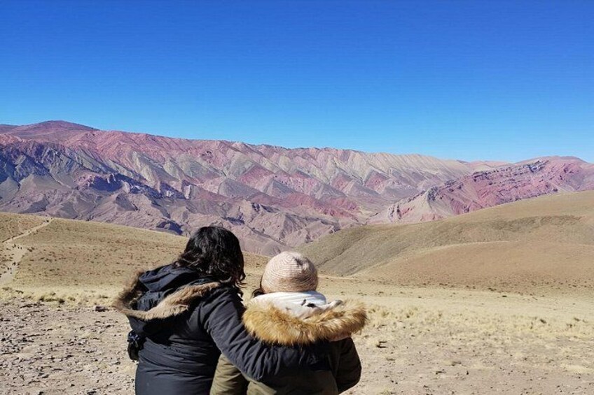 A woman and child standing on a barren landscape with mountains in the background. 3