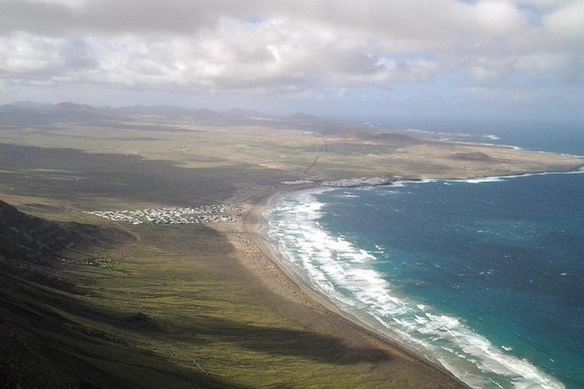A coastal landscape with a beach, ocean waves, and distant mountains. 3