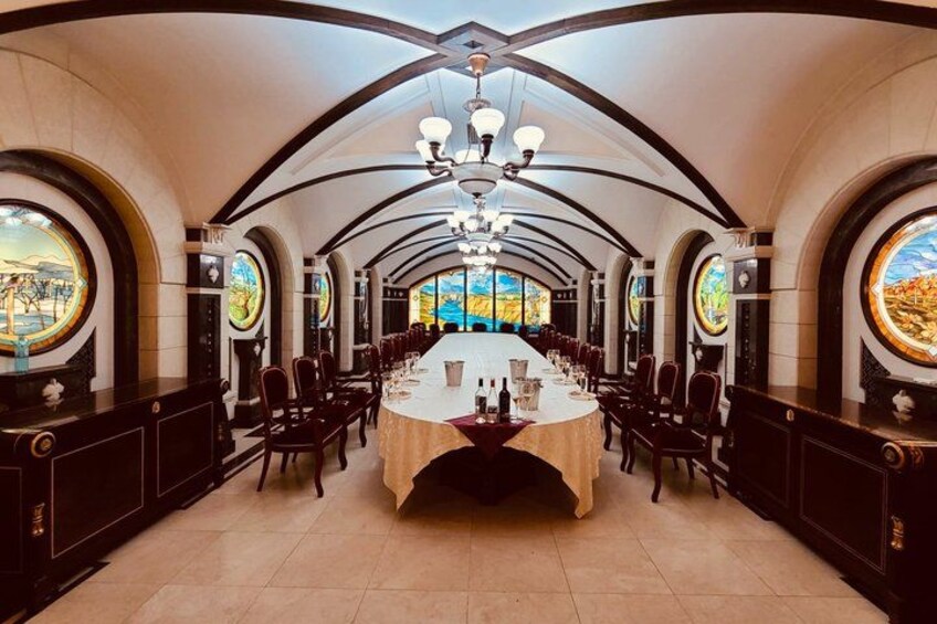 A grand dining hall with a long table, arched ceilings, and large windows with scenic views. 2