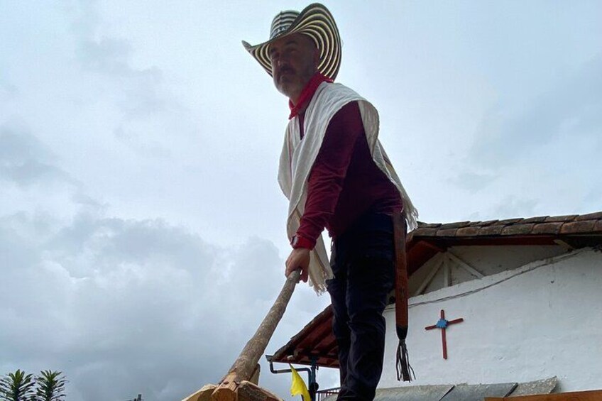 A person in a striped hat and red vest working on a roof, with a cross on the building. 2