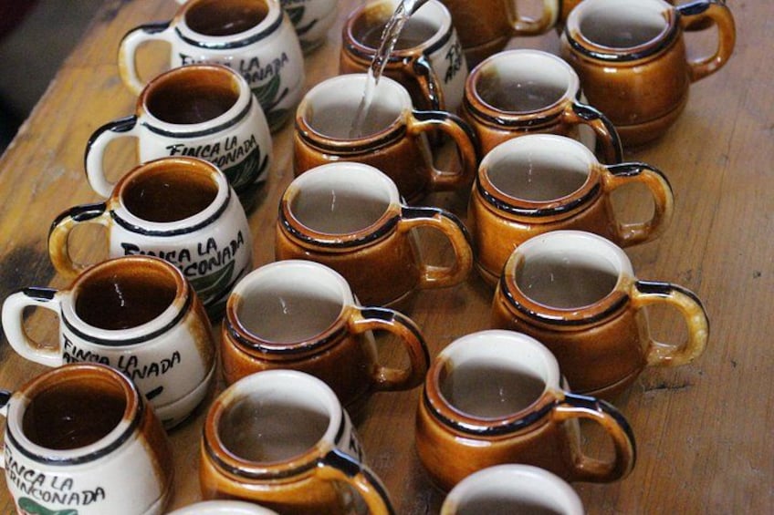 A collection of ceramic coffee cups with handles, some filled with coffee, arranged on a wooden surface. 2