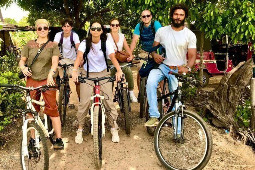 Un gruppo di persone in bicicletta in un ambiente naturale, con alberi e un sentiero sterrato. 2