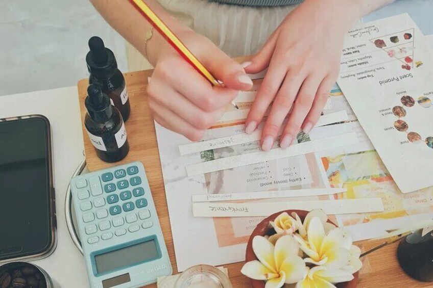 Una persona scrive su un biglietto con una matita, circondata da diversi articoli di cancelleria e una calcolatrice su una scrivania. 1